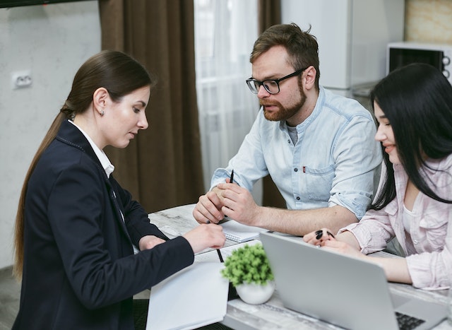 Person in a suit sitting down and reviewing documents with two other people